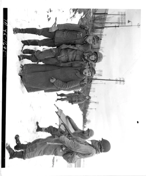 Prisioneros alemanes capturados al sur de Colmar escoltan a un soldado estadounidense herido fuera de la zona de combate, febrero de 1945