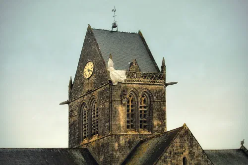 Iglesia de Sainte-Mère-Église con el maniquí de un paracaidista colgado del campanario, en homenaje a John Steele